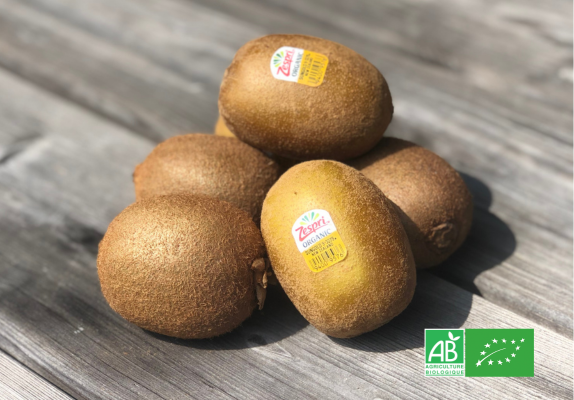 Kiwis Zespri bio posés sur une table en bois avec le label AB visible.